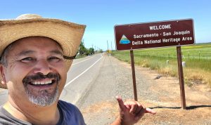 Hood Community Council Member Mario Moreno in front of a new sign welcoming motorists to the Sacramento-San Joaquin Delta National Heritage Area (PHOTO: ©Mario Moreno 2023 - used with permission)