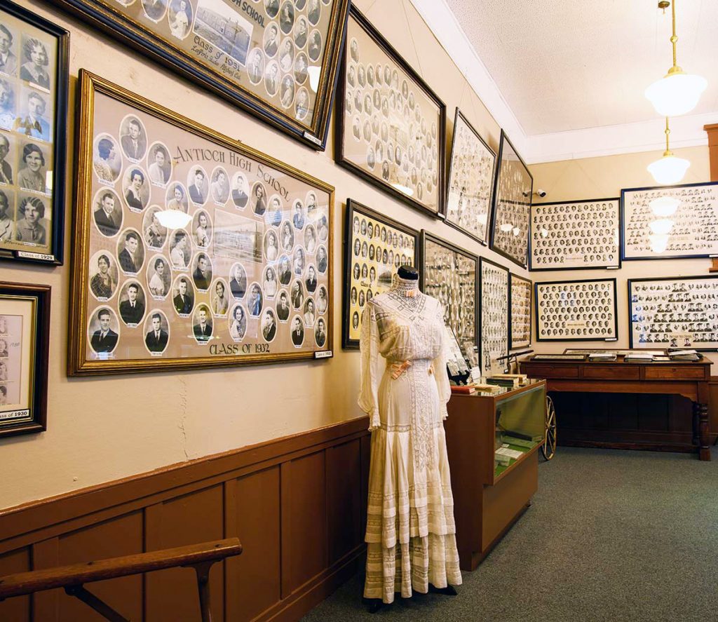 A woman's white dress from the Victorian era and posters of class photos