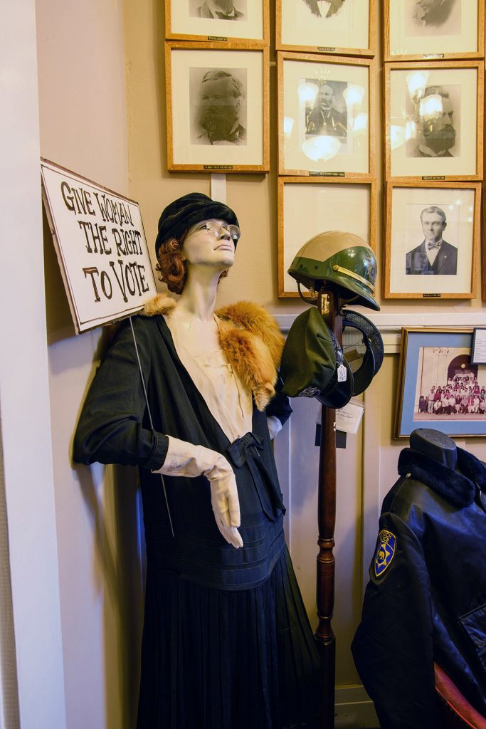 A mannequin clad in 1920s clothing and carrying a sign saying "Give women the right to vote"