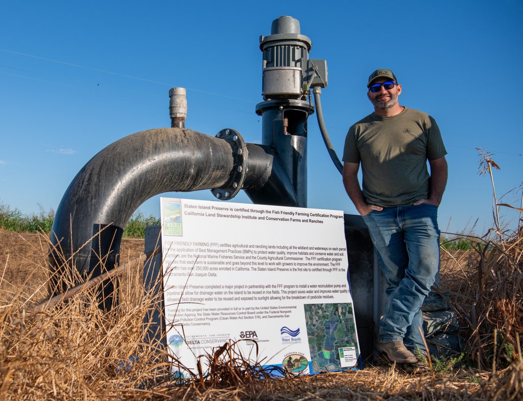 Man standing in front of a pump next to a sign