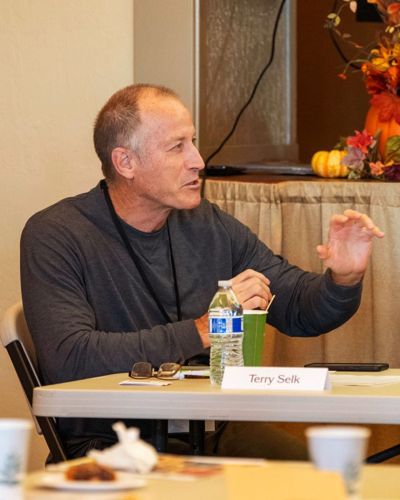 Man gesturing as she speaks to fellow members of a panel