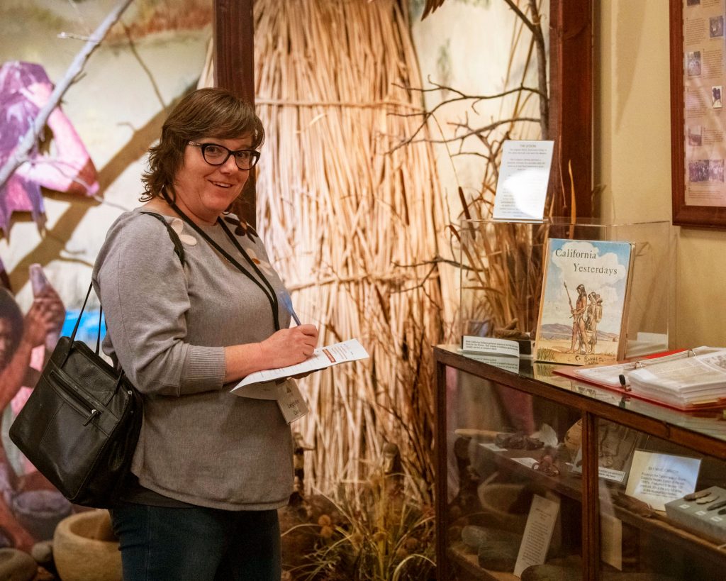 Woman writing on a piece of paper by a museum display