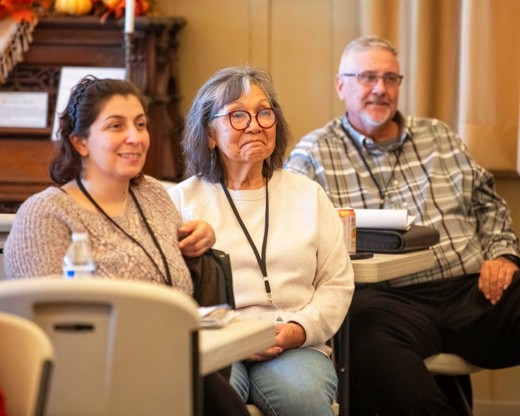 Audience members smiling in reaction to a speaker