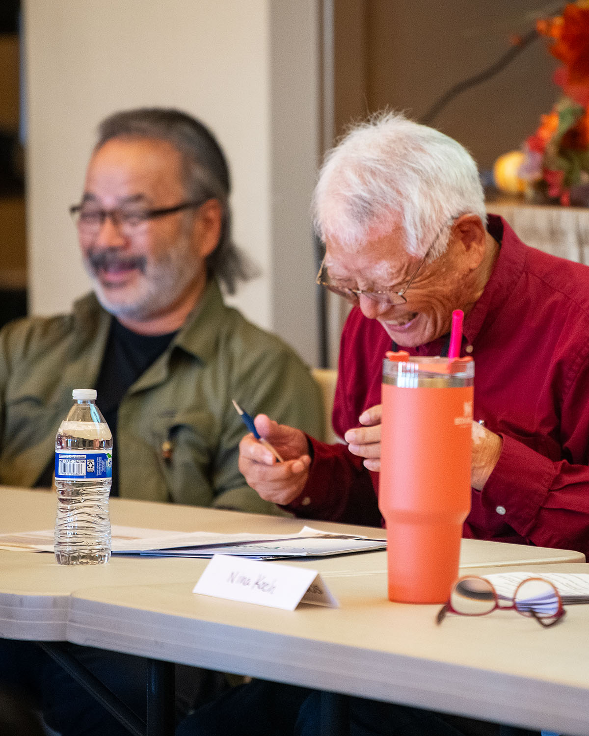 Two men at a speaker table laughing