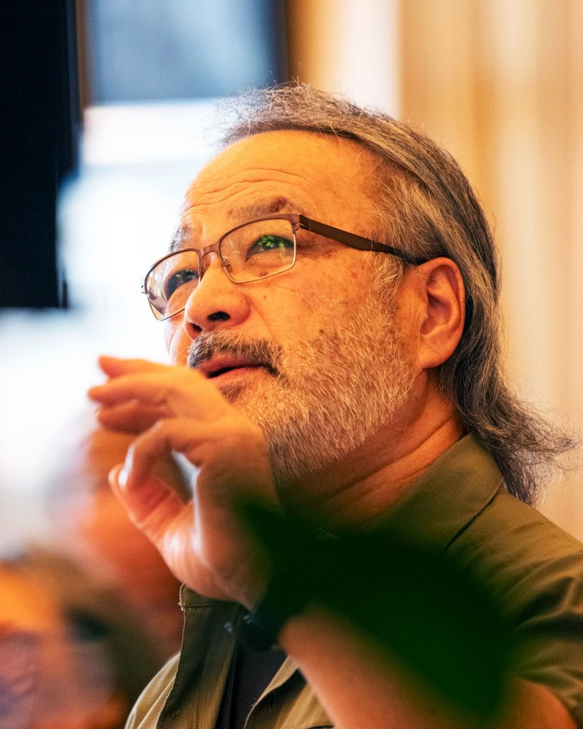 A speaker gestures as he looks up at a screen