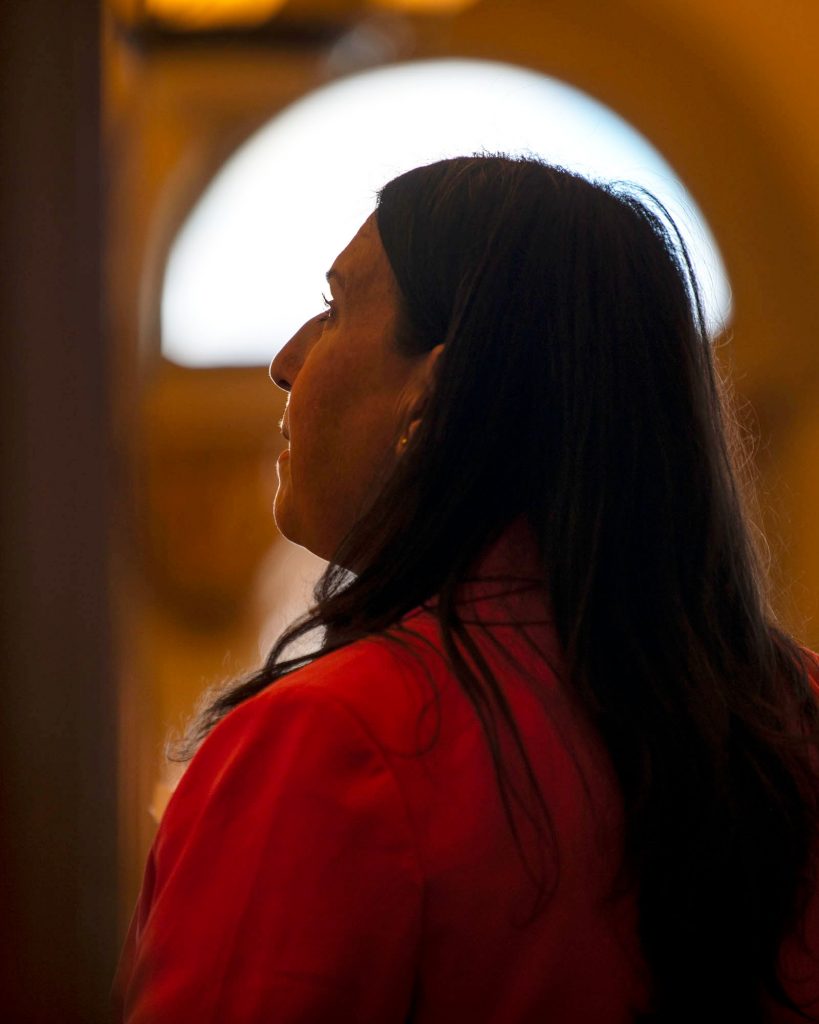 A woman backlit by a window looks out to her audience