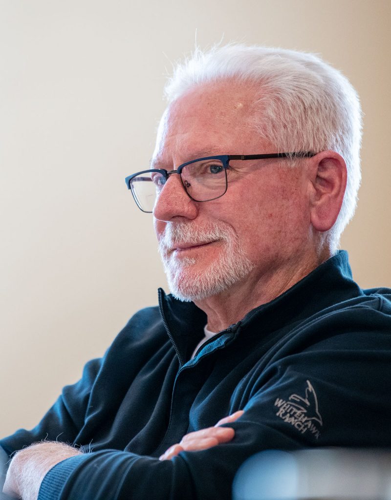 A man gazes forward with arms crossed