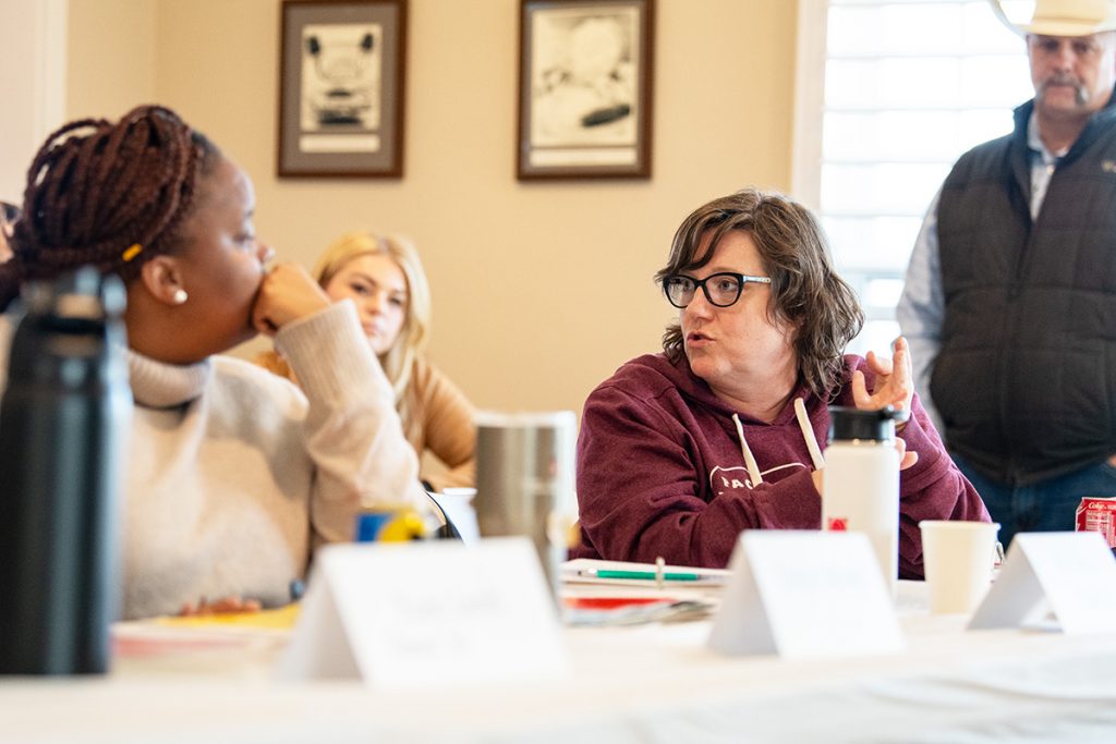 A woman at a conference table gestures as she speaks