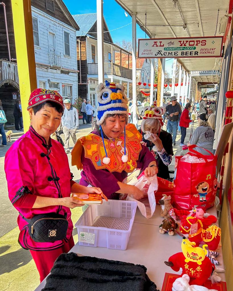 Women in festive Chinese New Year garb at a display table