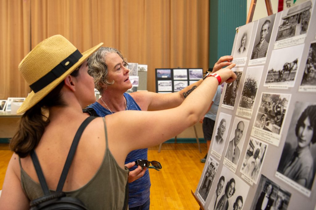 Two women pointing at historical photos
