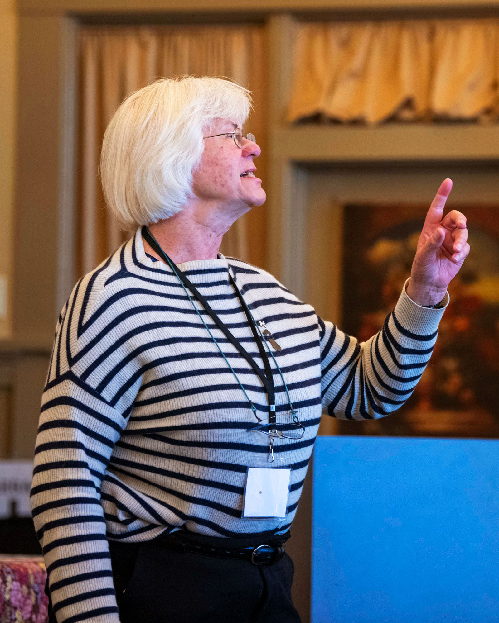 A woman pointing into the air as she speaks