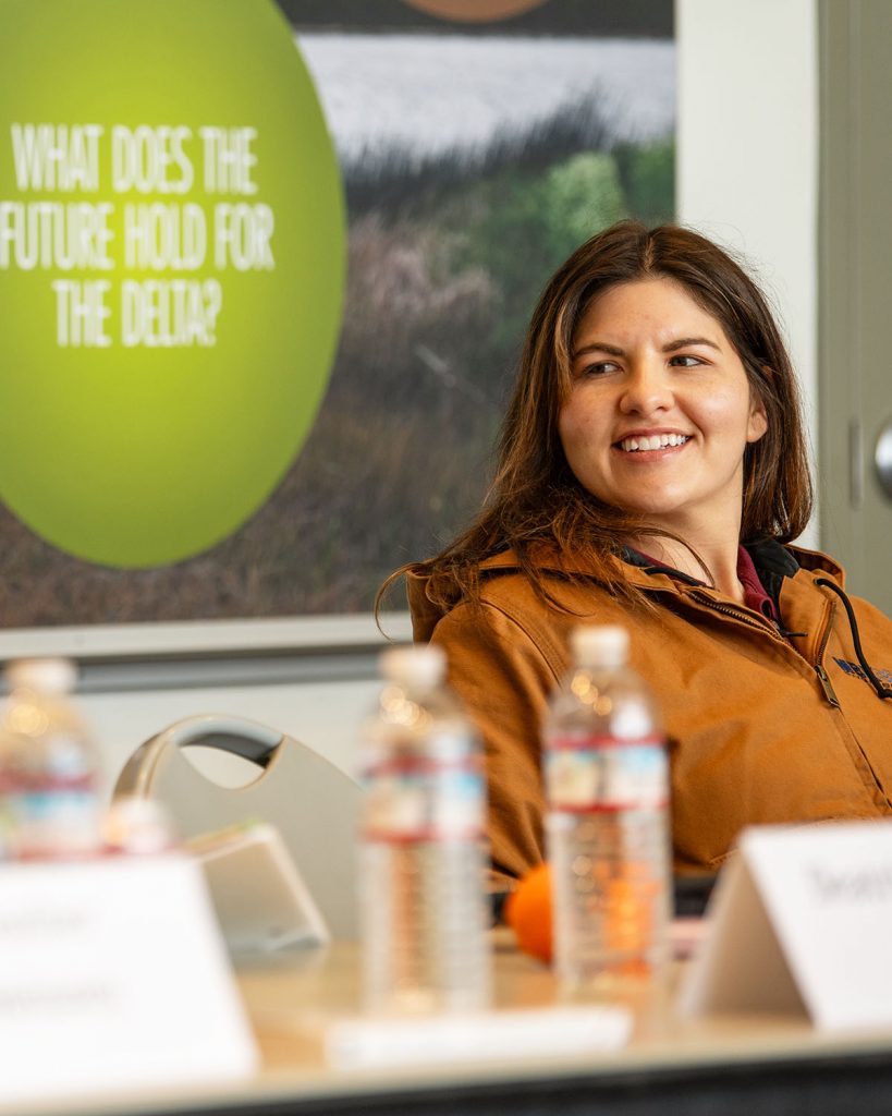 A woman smiles at what a speaker next to her is saying.