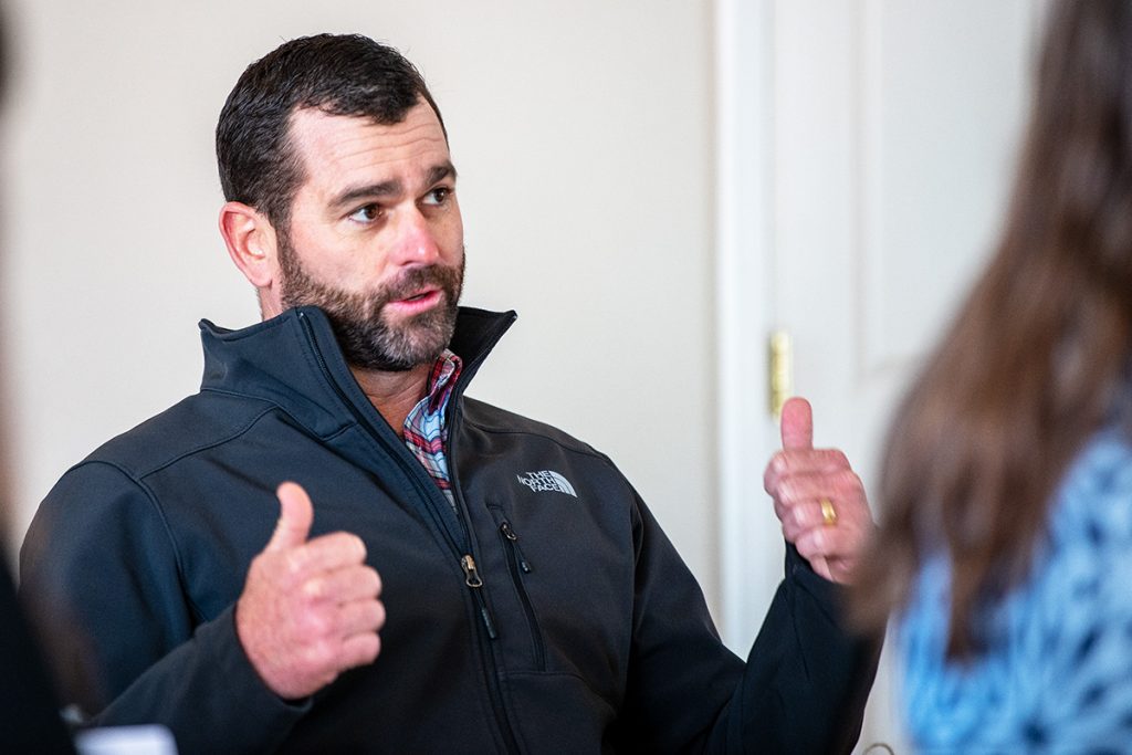 A man at a conference table holds two thumbs up in an "outta here" gesture.