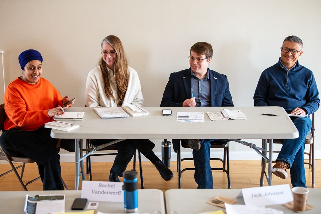 Four people at a conference table smile as they engage in an activity