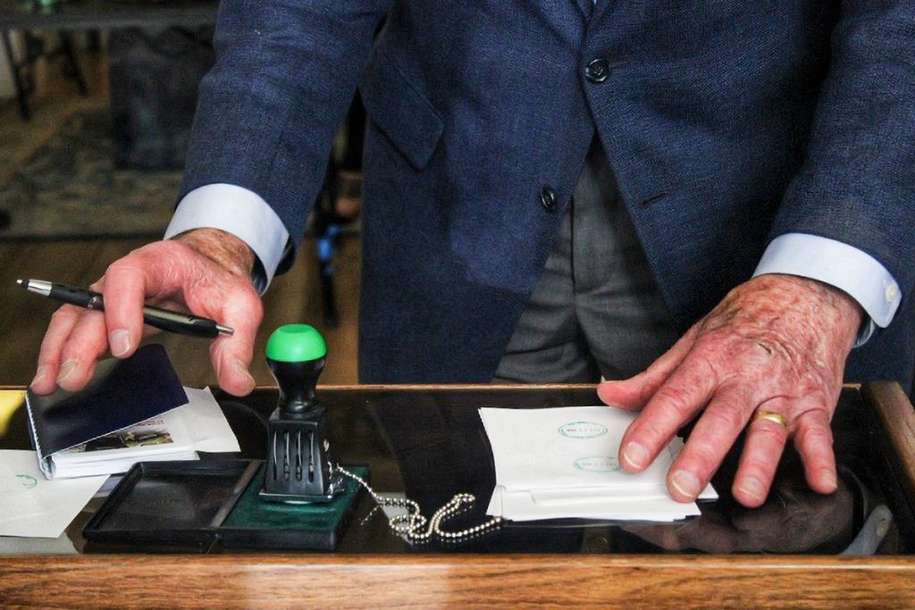 A man's hands on a table with a rubber stamp