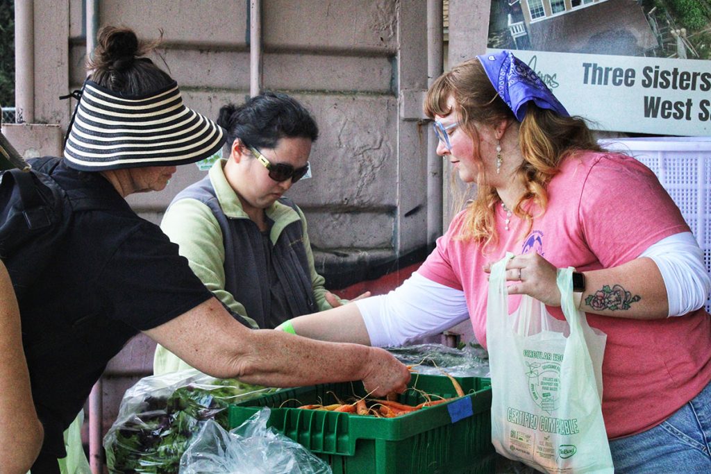 Women choosing vegetables from baskets