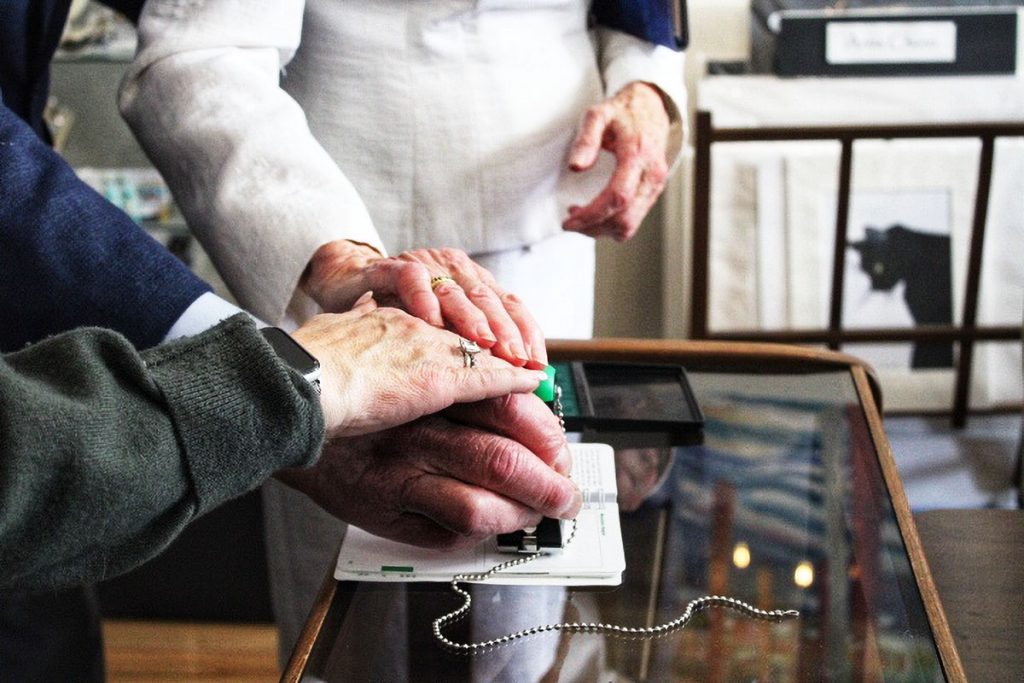 Three hands press down a rubber stamp