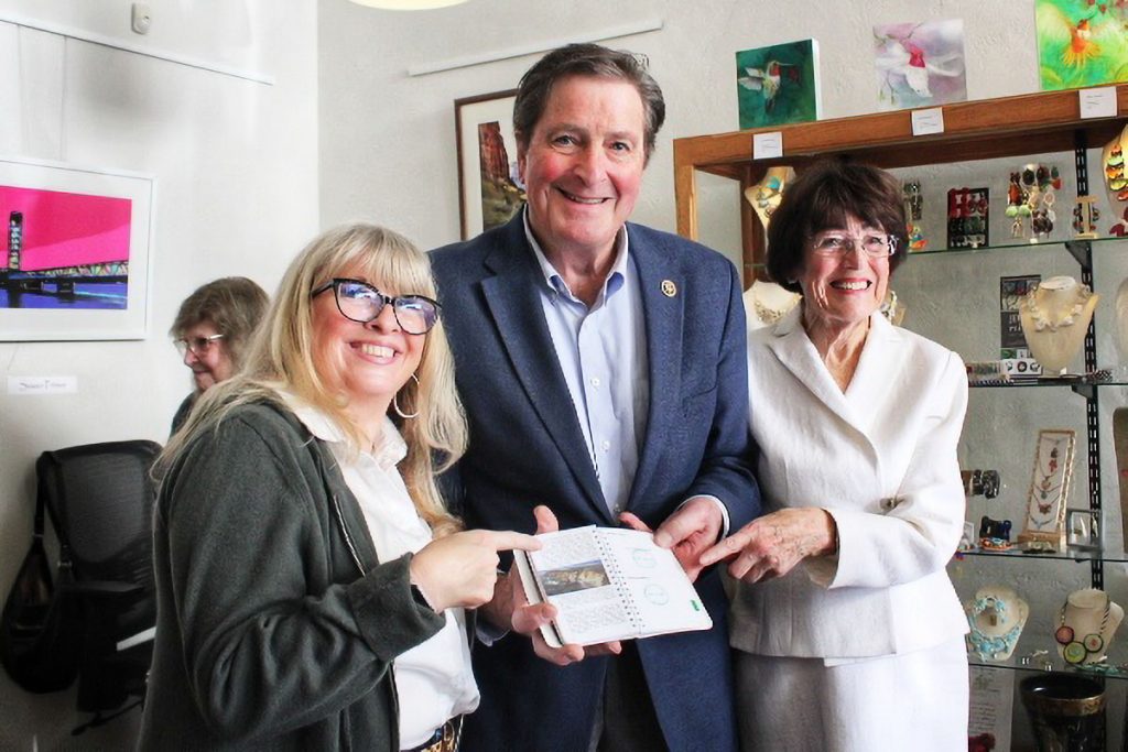 Two women and a man hold up a freshly stamped passport