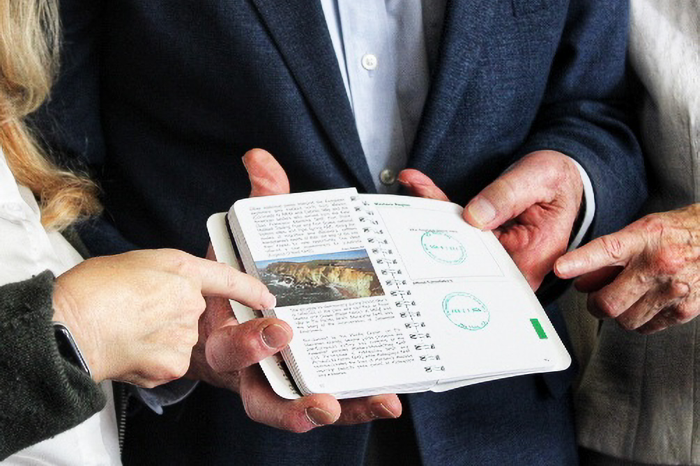 Closeup of three hands holding a freshly stamped passport