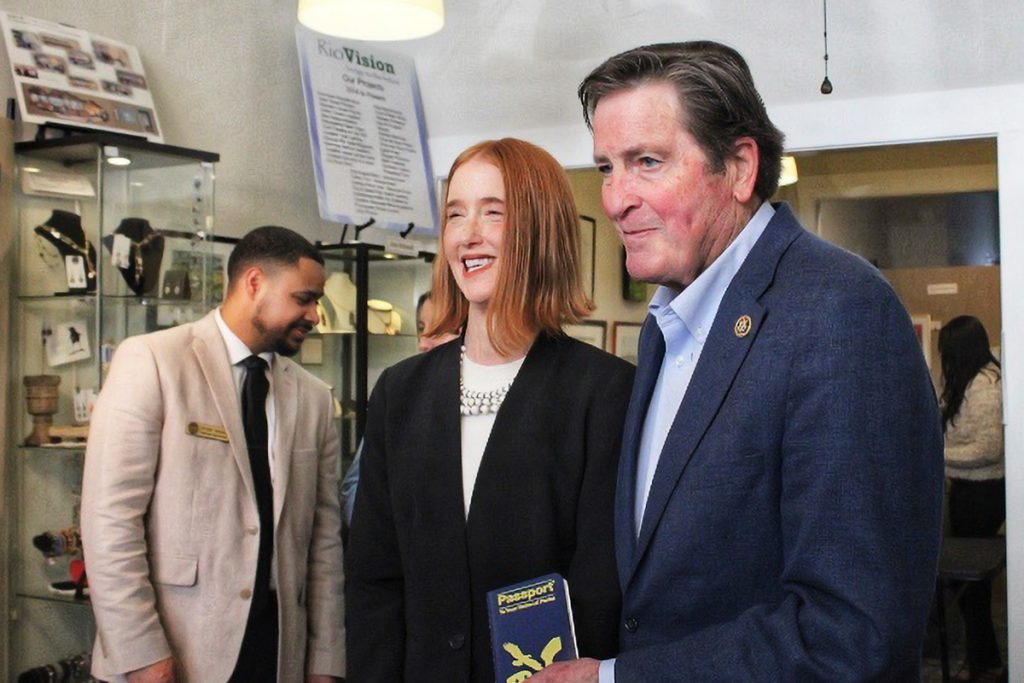 A man holding a passport book poses with a smiling woman