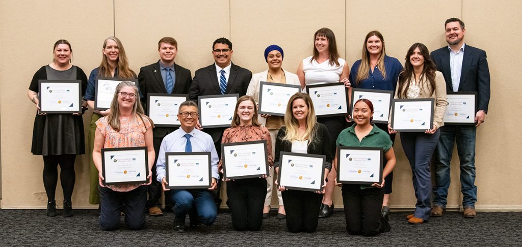 Photo of 14 men and women holding framed certificates