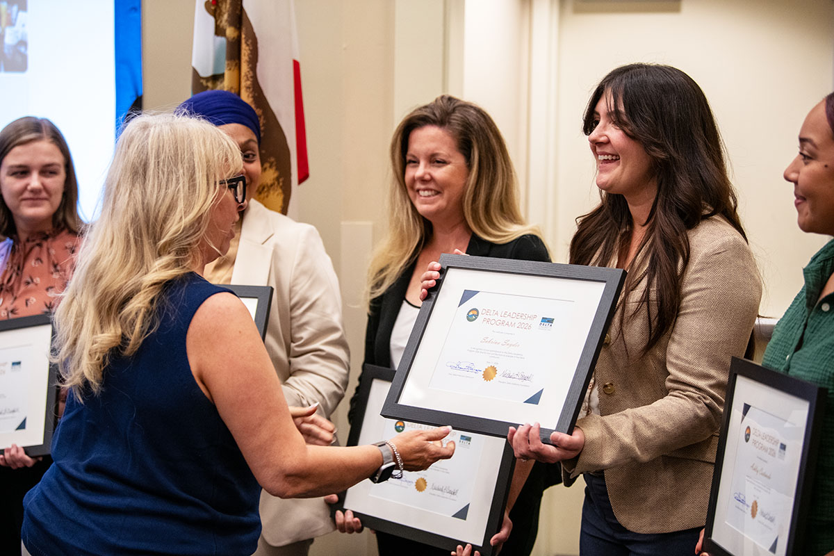 Woman presenting a framed certificate to a woman standing in a line of recipients