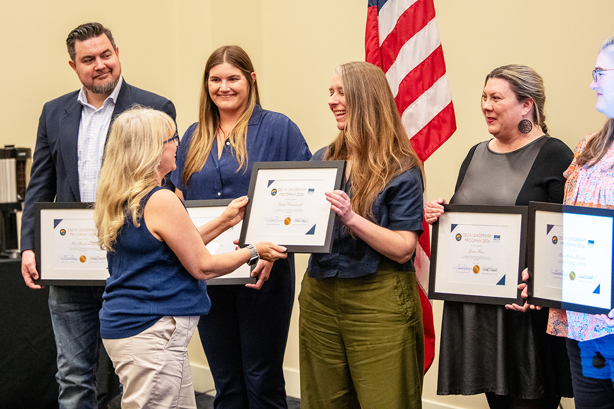 Woman presenting a framed certificate to a woman standing in a line of recipients